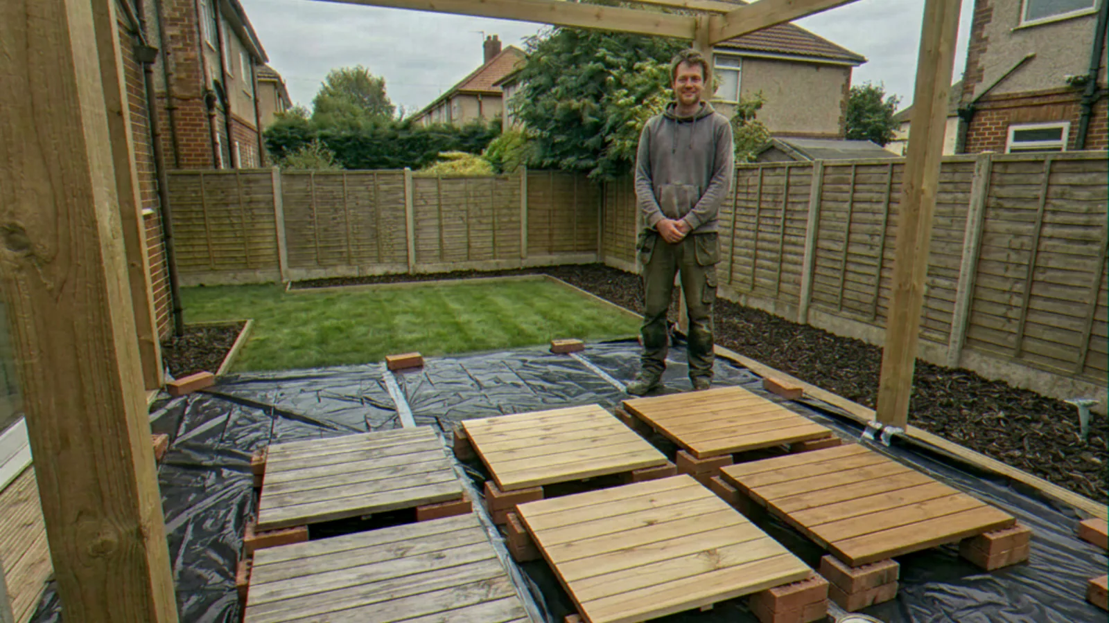 Chester Humborough standing behind decking test panels in a South London garden